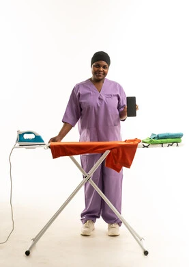 عاملة منزلية أفريقية مع هاتف ذكي وطاولة كي