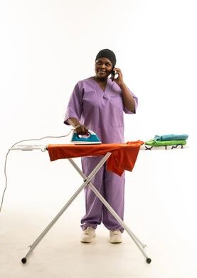 عاملة منزلية أفريقية تقوم بكي الملابس وتتحدث بالهاتف عاملة منزلية أفريقية تقوم بكي الملابس وتتحدث بالهاتف