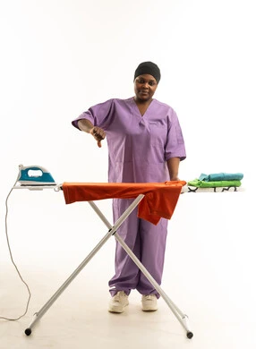 امرأة أفريقية بزي التمريض تشير بعدم الرضا خلف طاولة الكي