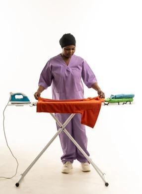 امرأة أفريقية تكوي الملابس بزي العمل الأرجواني