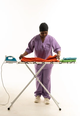 African Domestic Worker Ironing Clothes on White Background