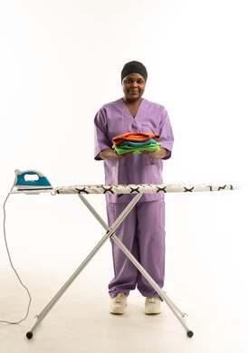 African Housekeeper with Folded Laundry and Ironing Board