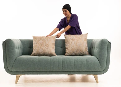 عاملة منزلية آسيوية ترتب الوسائد على الأريكة