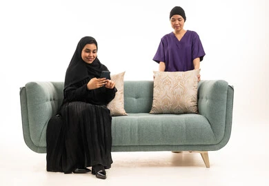 امرأة عربية مع هاتف ذكي وعاملة منزلية آسيوية