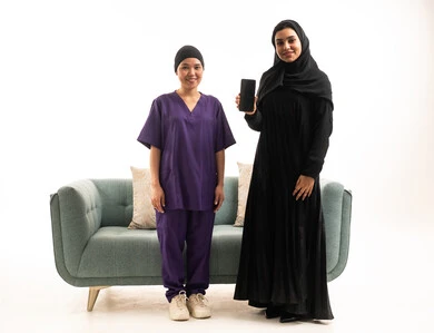 امرأة سعودية وعاملة منزلية مع هاتف ذكي