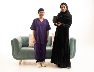 امرأة سعودية وعاملة منزلية مع هاتف ذكي في استوديو