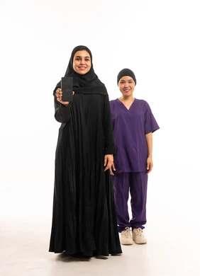 امرأة سعودية وعاملة منزلية تمسكان هاتف ذكي