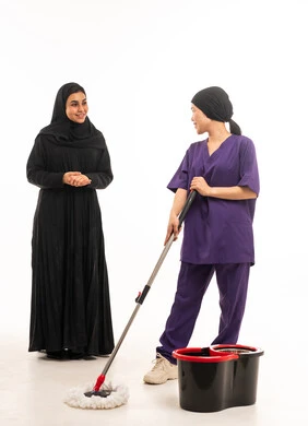 امرأة سعودية وعاملة منزلية مع معدات التنظيف