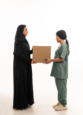 امرأة سعودية وعاملة منزلية مع صندوق على خلفية بيضاء