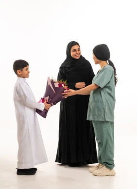 طفل سعودي يقدم الزهور لعاملة منزلية بخلفية بيضاء طفل سعودي يقدم الزهور لعاملة منزلية بخلفية بيضاء
