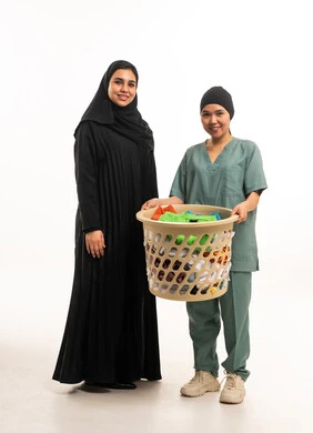 امرأة سعودية وعاملة منزلية مع سلة غسيل