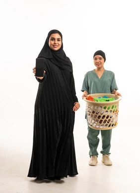 امرأة سعودية وعاملة منزلية مع سلة غسيل وهاتف امرأة سعودية وعاملة منزلية مع سلة غسيل وهاتف