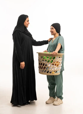 امرأة سعودية مع عاملة منزلية تحمل سلة غسيل