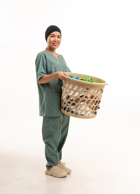 امرأة آسيوية بزي العمل تحمل سلة غسيل