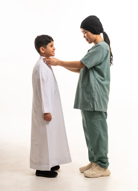 عاملة منزلية تساعد طفل سعودي في ارتداء الثوب