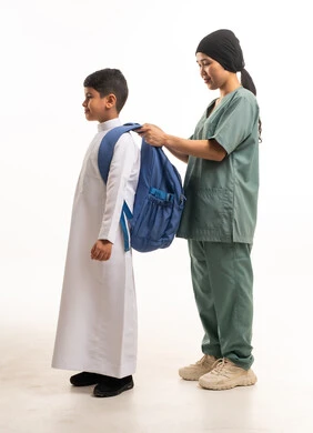 عاملة منزلية تساعد طفل سعودي بحقيبة المدرسة