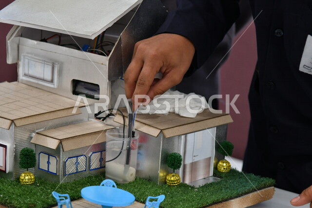 صورة مقربة ليد رجل يقوم بإجراء تجارب الري والزراعة على مجسم خشبي ، مختبر علمي زراعي ، بحوث زراعية ، الري والزراعة ، تجارب علمية تثقيفية