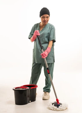 عاملة نظافة آسيوية بزي أخضر وممسحة أرضيات