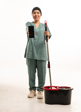 عاملة منزلية تمسك هاتف ذكي مع أدوات التنظيف