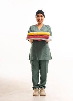 عاملة منزلية ترتدي زياً رسمياً وتحمل غسيل مطوي