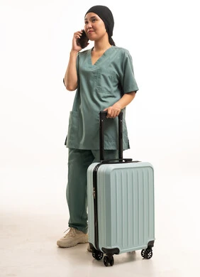 عاملة منزلية مع حقيبة سفر تتحدث بالهاتف المحمول