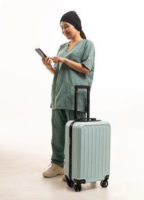 عاملة منزلية مع حقيبة سفر وهاتف ذكي في الاستوديو