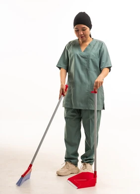 عاملة نظافة آسيوية بزي العمل والمكنسة