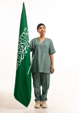 عاملة منزلية تحمل العلم السعودي بزي العمل الأخضر