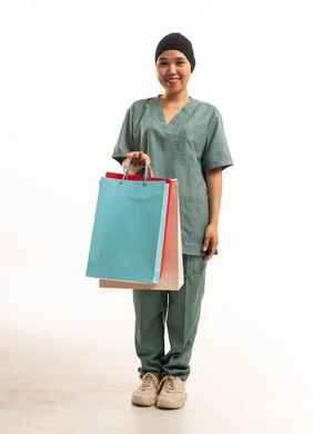 عاملة منزلية تحمل حقائب تسوق ملونة بخلفية بيضاء