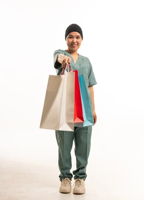 عاملة منزلية تحمل حقائب تسوق ملونة بخلفية بيضاء