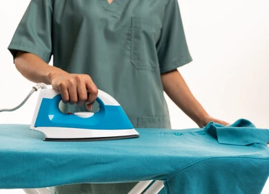 شخص بزي طبي يقوم بكي قميص أزرق