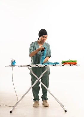 عاملة منزلية آسيوية تقوم بطي الملابس في الاستوديو