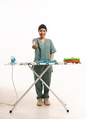 عاملة منزلية آسيوية تشير بالإبهام بجانب طاولة الكي