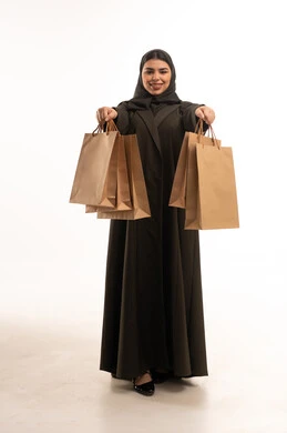 امرأة سعودية تحمل أكياس تسوق ورقية بنية