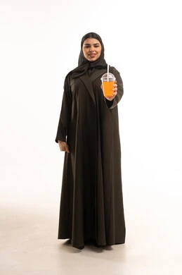 امرأة سعودية بالعباءة السوداء تحمل عصير برتقال