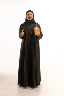 امرأة سعودية مع عصير برتقال وعلامة إعجاب في استوديو