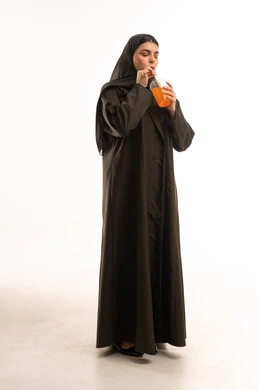 امرأة سعودية بالعباءة تشرب عصير البرتقال