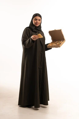 امرأة سعودية بالعباءة تحمل علبة بيتزا في الاستوديو