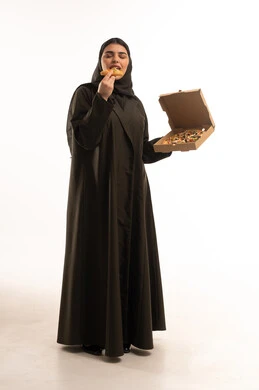 امرأة سعودية بالعباءة السوداء تأكل البيتزا