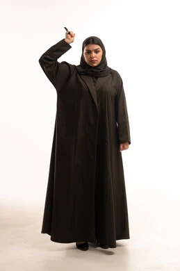 امرأة سعودية بالعباءة ترفع قلماً في الاستوديو