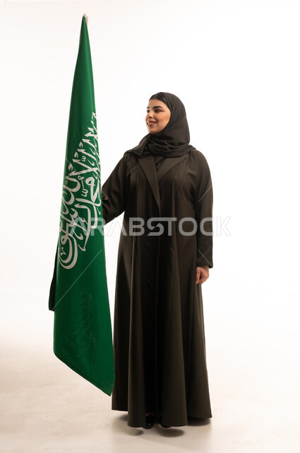 امرأة سعودية بالعباءة مع علم السعودية