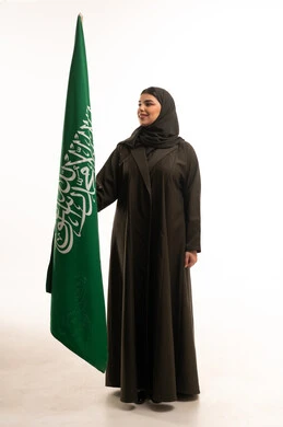 امرأة سعودية بالعباءة مع علم السعودية