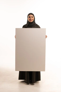 امرأة سعودية بالعباءة تحمل لوحة بيضاء فارغة