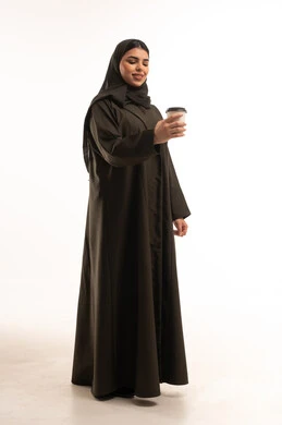 امرأة سعودية تحمل كوب قهوة بالعباءة السوداء