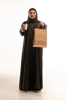 امرأة عربية تحمل حقيبة تسوق وكوب قهوة