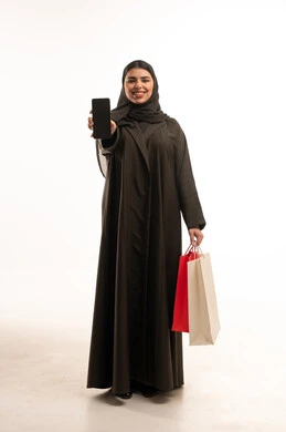 امرأة سعودية مع هاتف ذكي وحقائب تسوق