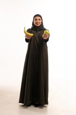 امرأة سعودية تحمل فاكهة الموز والتفاح الأخضر