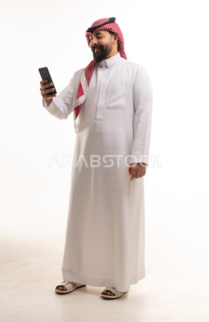 رجل سعودي بالزي التقليدي يستخدم الهاتف الذكي