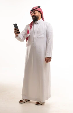 Saudi Man in Traditional Thobe Using Smartphone