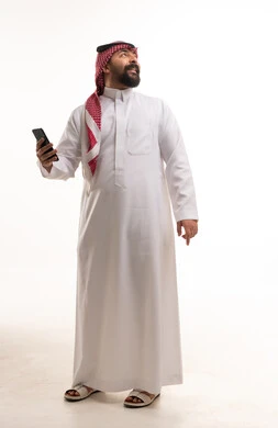 رجل سعودي بالزي التقليدي يمسك هاتفاً ذكياً